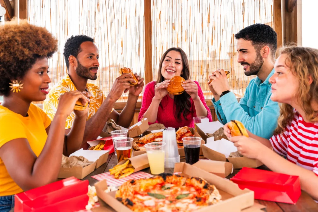 amici a un tavolo mentre mangiano cibo spazzatura