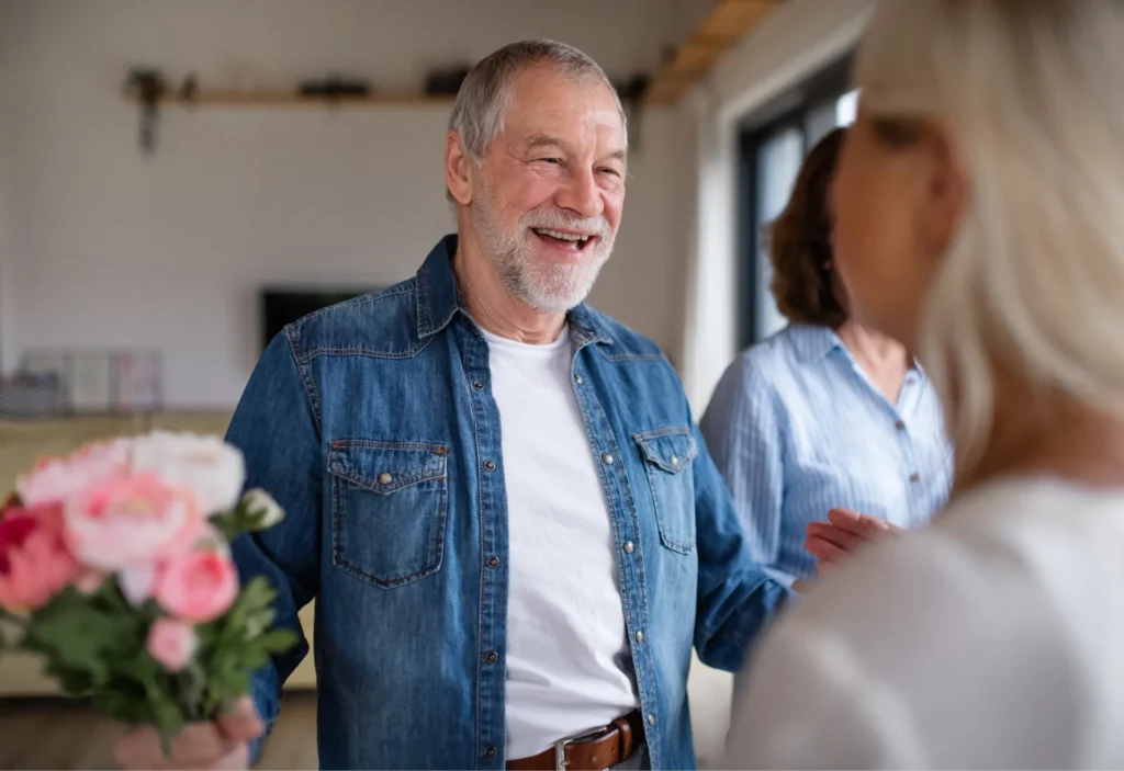 uomo di mezza età pieno di energia che accoglie una donna con un mazzo di fiori