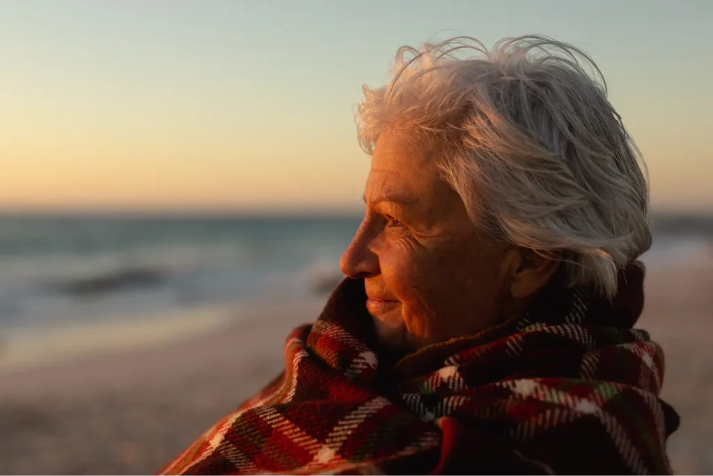 Donna che si gode mezzora di sole di fronte al mare per la dose giornaliera di vitamina d