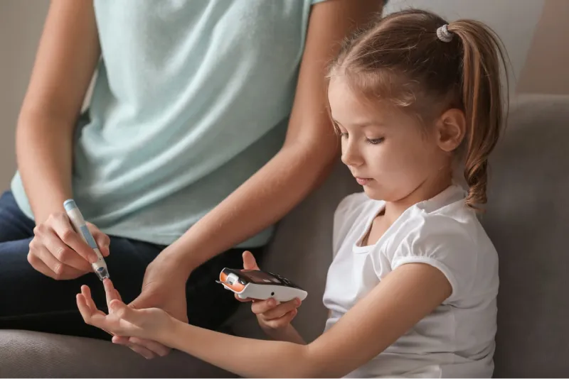 Bambina che si misura la glicemia con sua madre