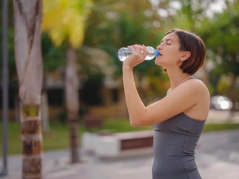 Donna al parco che beve acqua dalla bottiglia