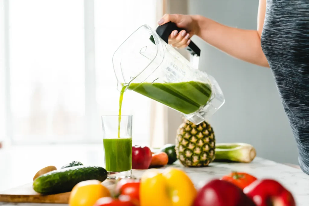 Foto di donna che versa un frullato appena realizzato con frutta e verdura