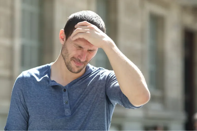 Uomo che si tocca la fronte perché ha la pressione bassa