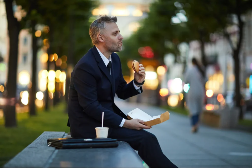 Manager uomo che consuma velocemente un pranzo da fast food