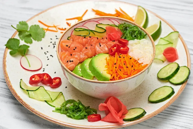 foto di poke con riso, salmone, avocado, carote, alghe e peperoncino