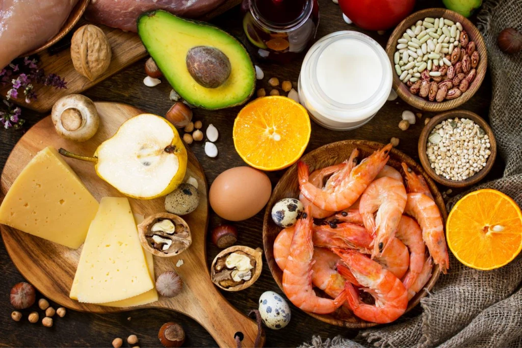 Rappresentazione di alimenti sani: avocado, arancia, pere, legumi, gamberi, formaggi