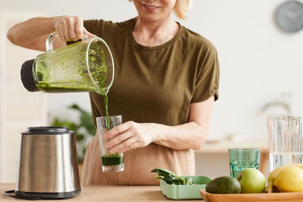 Donna che prepara frullato verde di frutta e verdura