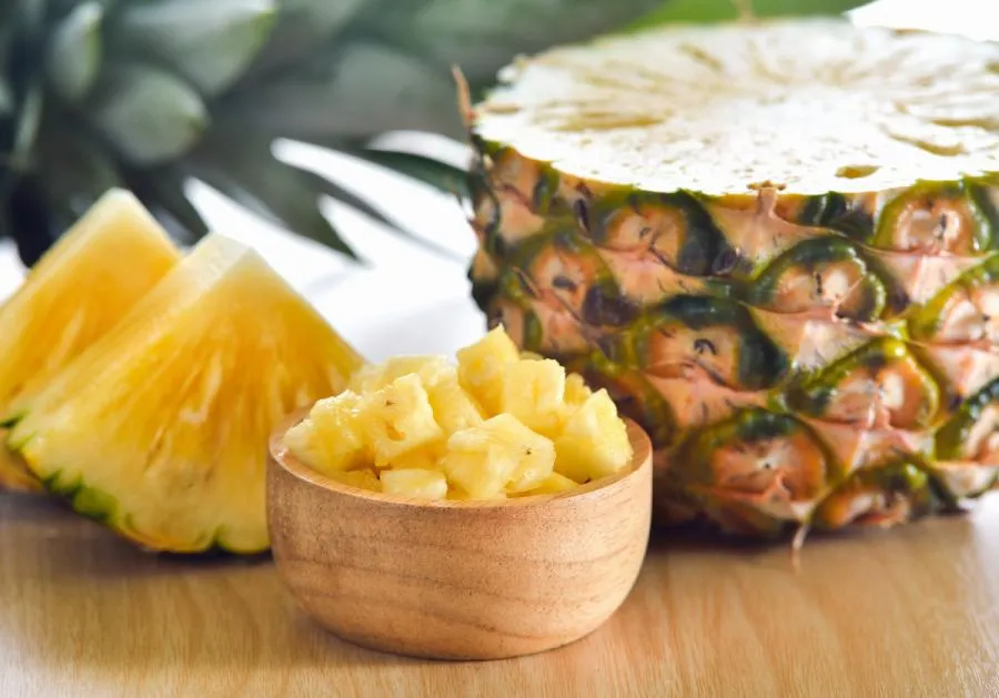 Immagine di ananas tagliato in vari formati disposto su un tavolo in legno