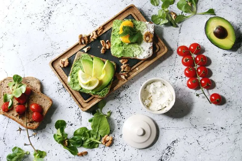 Immagine di avocado servito con diversi abbinamenti tra cui basilico, pomodorini e formaggio