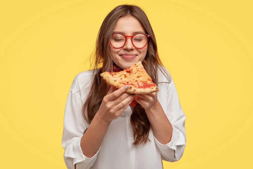 ragazza che mangia ciò che le piace: uno spicchio di pizza