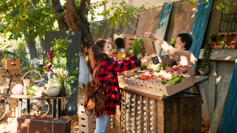 donna che prende un sacchetto di carta con delle verdure inun mercato settimanale