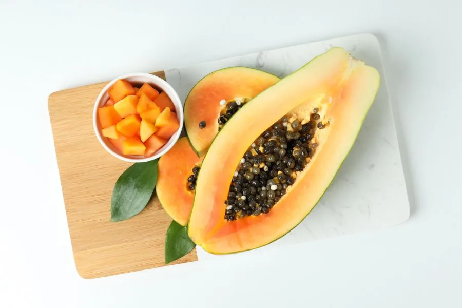 Immagine di una papaya tagliata a metà disposta su un tagliere