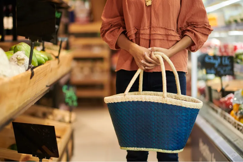 donna che tiene in mano una borsa di paglia al supermercato