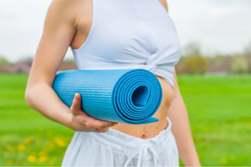 foto di busto di una ragazza con un tappeto yoga che si mantiene in forma