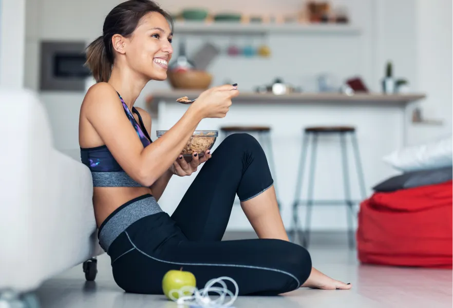 donna seduta per terra che mangia dopo aver fatto sport