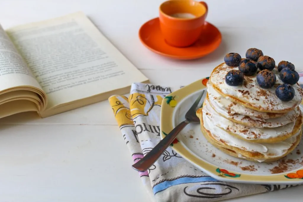piatto con pancakes decorati con mirtilli e yogurt, con una spolverata di cannella