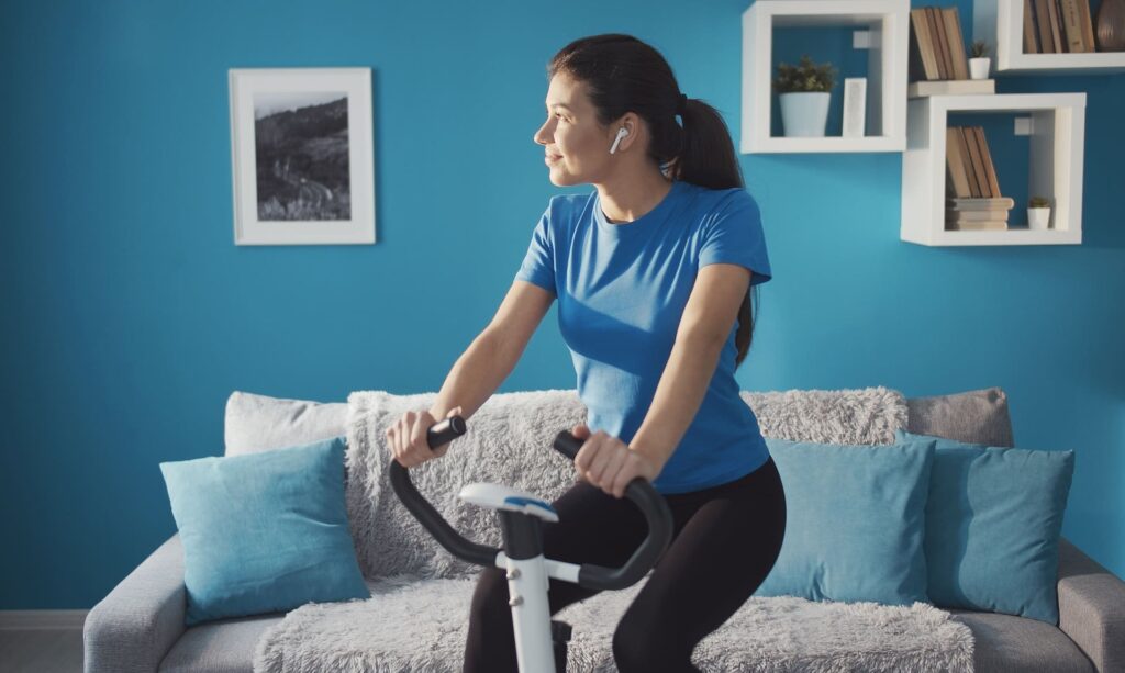 Ragazza che pedala alla cyclette in casa.