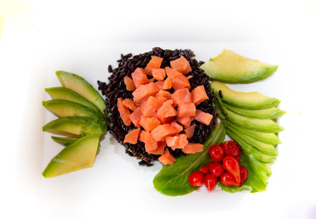 Piatto di riso venere con salmone e avocado.