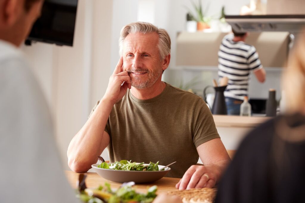 Primo piano di un uomo che pranza con un'insalata in famiglia.