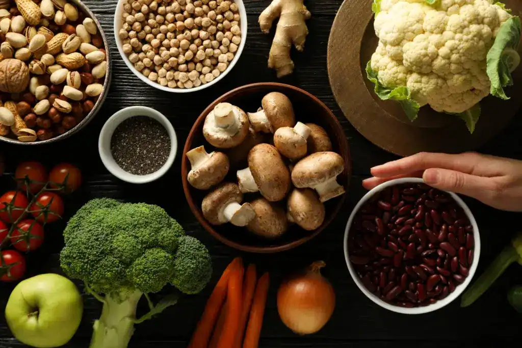 Diverse ciotole con dentro frutta secca, fagioli, funghi. Attorno ci sono verdure, frutta e spezie.